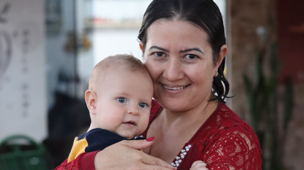 A woman smiles as she holds a baby