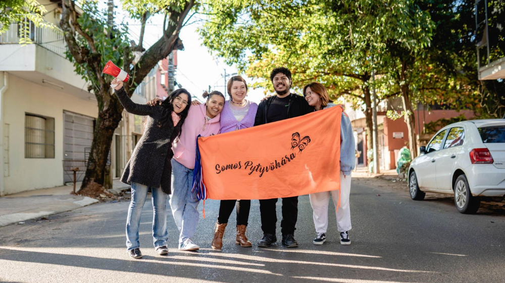 A group of young people hold a banner.