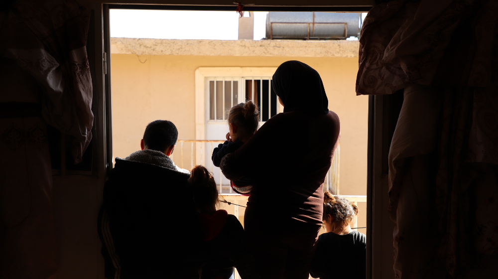  A woman and her children stand in the doorway of a shelter.