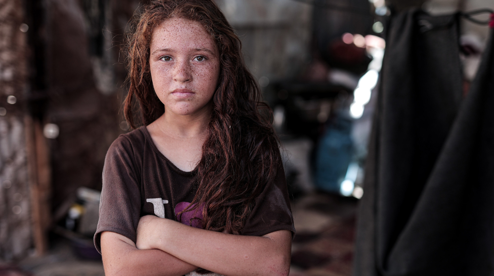 A young girl looks into the camera with her arms crossed