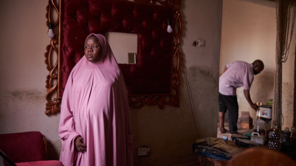 A woman in a pink chador stands in a flood-damaged home.