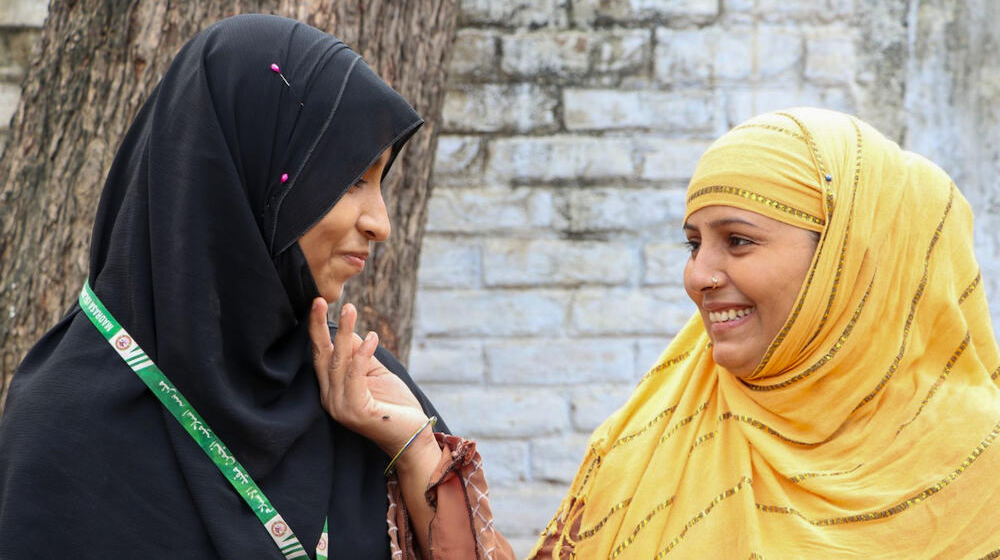 Two women smiling, one holding the chin of the other. 