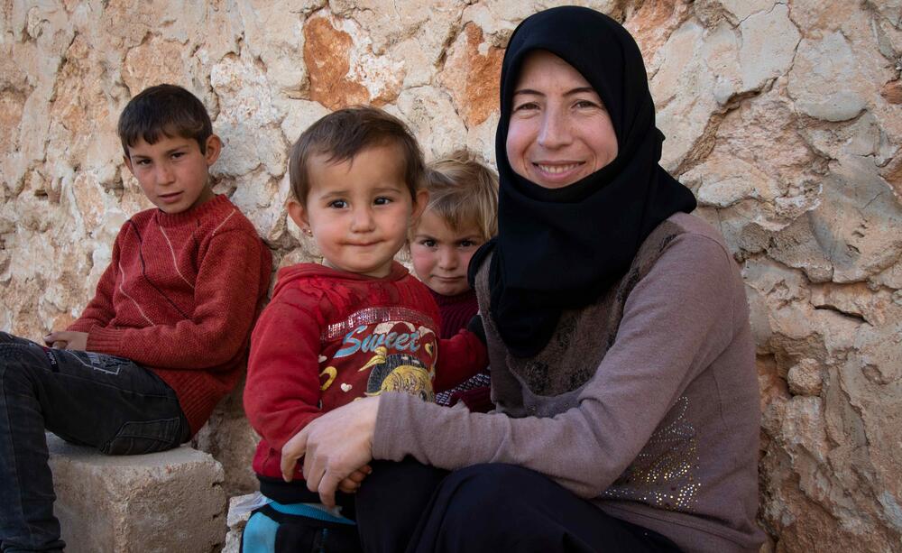 A mother and her three children smile for a family photo.