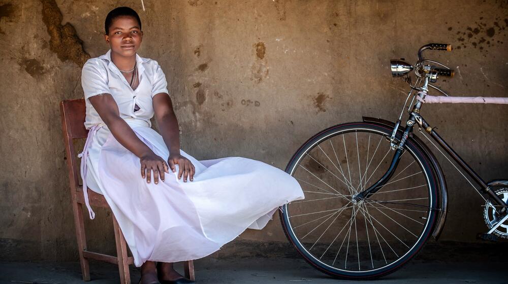 A woman sits with a bike.