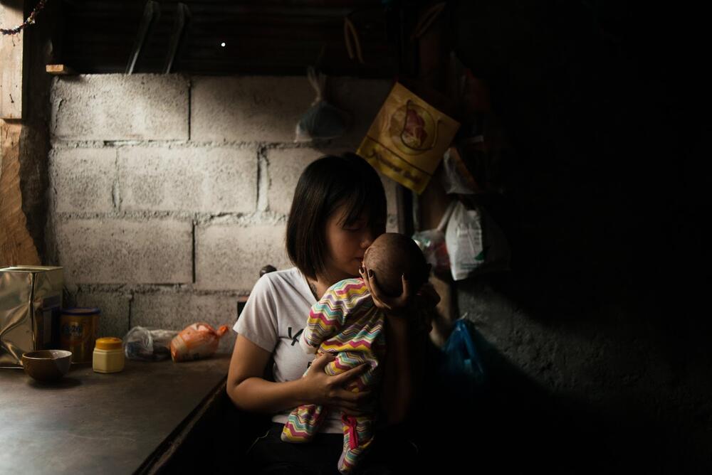 A young mother holds her child in her arms.