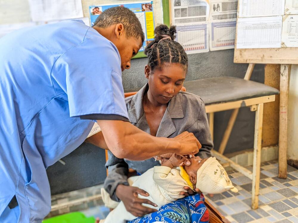 A doctor administers a vaccination to an infant held by his mother.