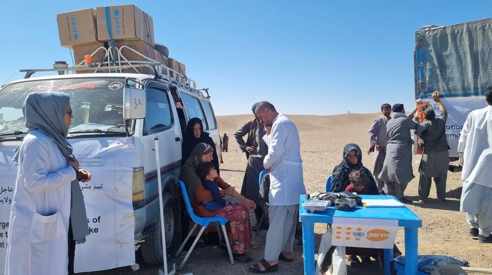 Un groupe de personnes assises à côté d’un véhicule. Des agent·e·s de santé s’occupent d’elles.