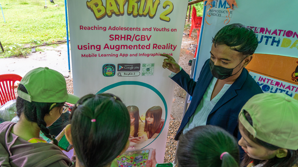 An educator demonstrates a mobile app with young people.