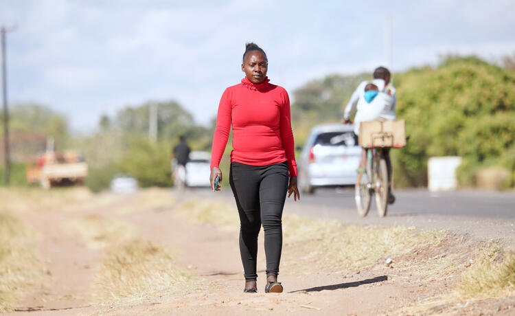 Une femme marche le long d’une route empruntée par des voitures et des vélos