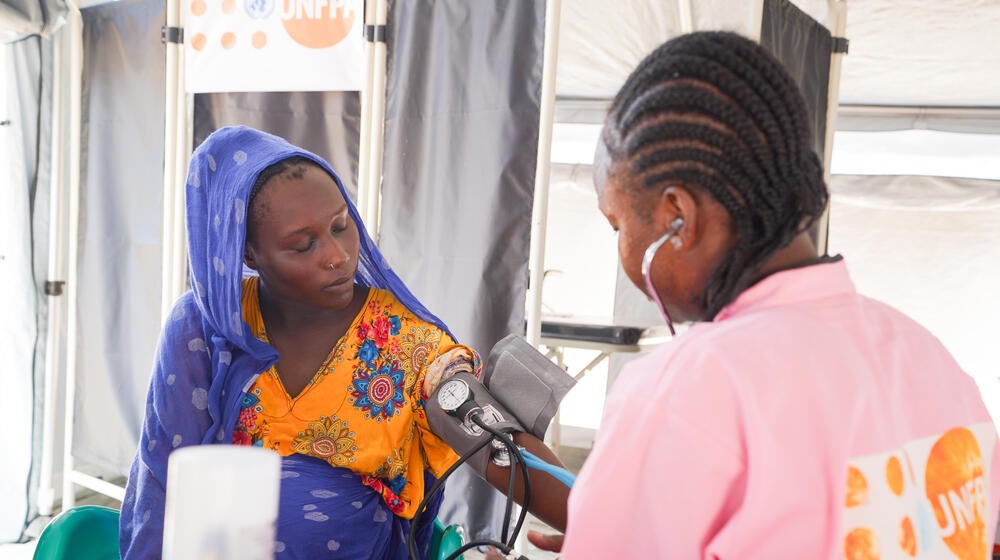 A pregnant woman from Chad receives medical services from a midwife.