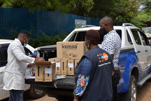 Supply packages in the back of a white pick-up truck are received by staff.  