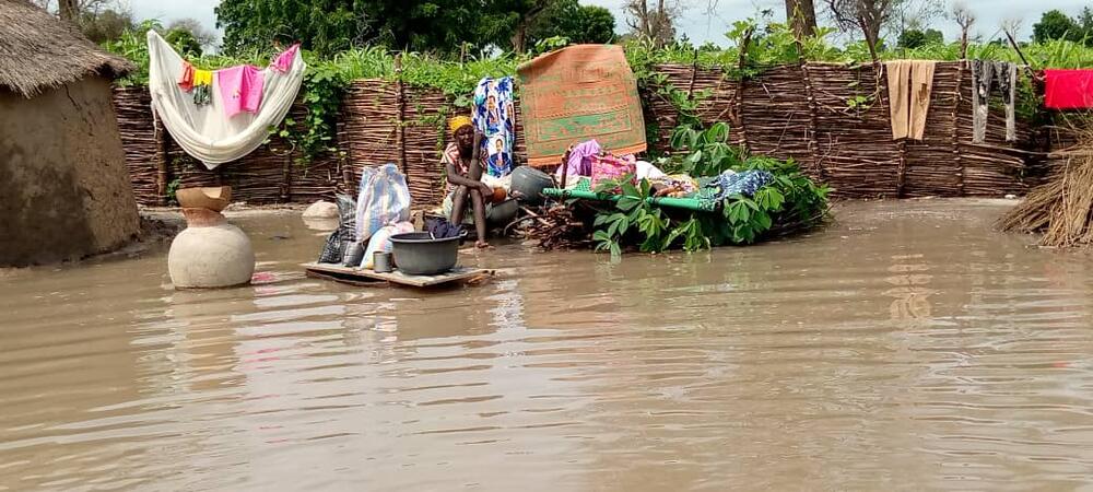 A woman sits amid her belongings surrounded by floodwater