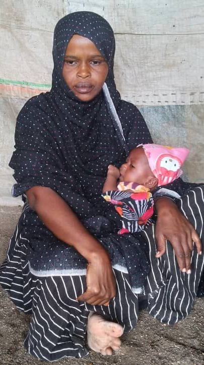 Ms. Bashir sits on the floor and holds her infant son.