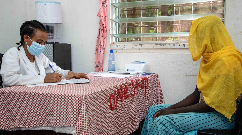 Femme anonyme assise à un bureau polyvalent, devant une doctoresse prenant des notes.