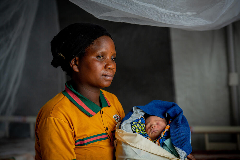 A woman holds a newborn baby.