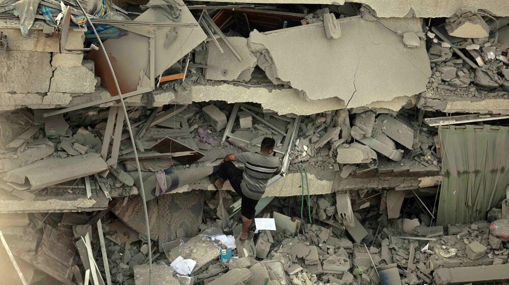 Un homme escalade les décombres d’un bâtiment lourdement bombardé.