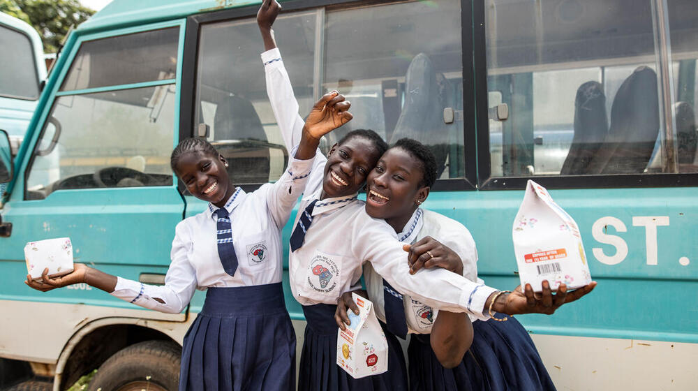 A group of girls with dignity kits smile.