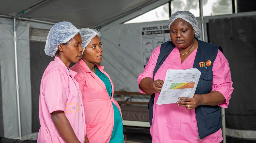 Tres parteras revisan registros médicos en un centro médico.