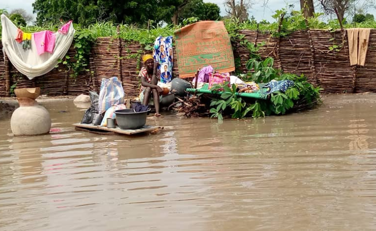 Una mujer sentada entre sus pertenencias rodeada de aguas de la inundación]