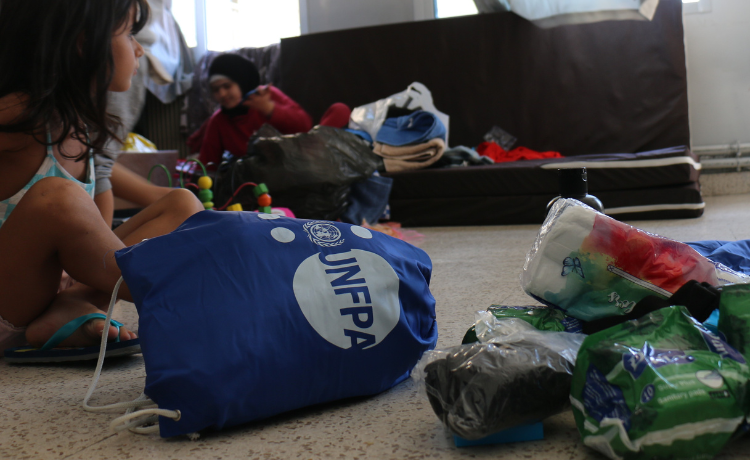  Un sac bleu floqué d’un logo blanc de l’UNFPA est couché sur le côté, près d’une petite pile de serviettes hygiéniques et d’autres produits d’hygiène.