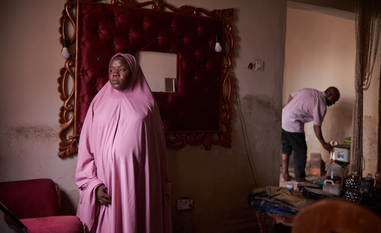 Une femme portant un hijab rose regarde sa maison, endommagée par les inondations.