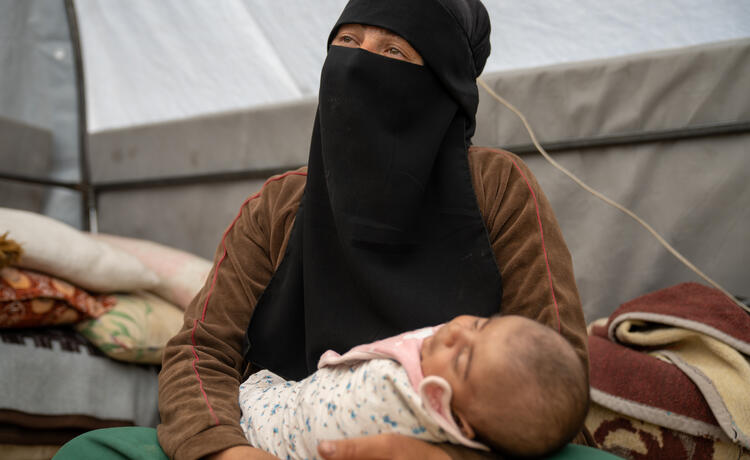 A woman holds a young child. 