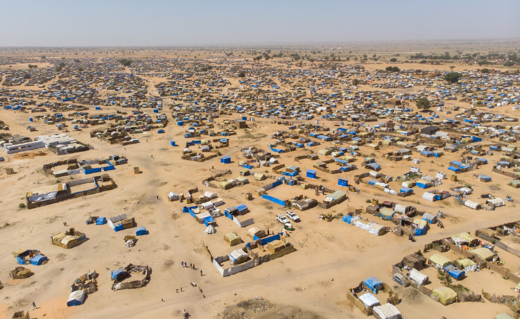 Vista aérea de muchas tiendas de campaña y casas improvisadas, rodeadas por terreno desértico