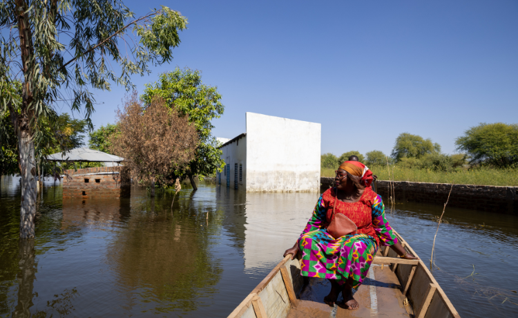 Una mujer sentada en una canoa contempla los edificios sumergidos