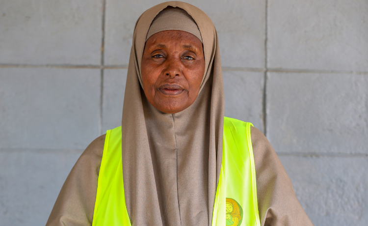 Une femme portant un gilet jaune réfléchissant regarde l’objectif