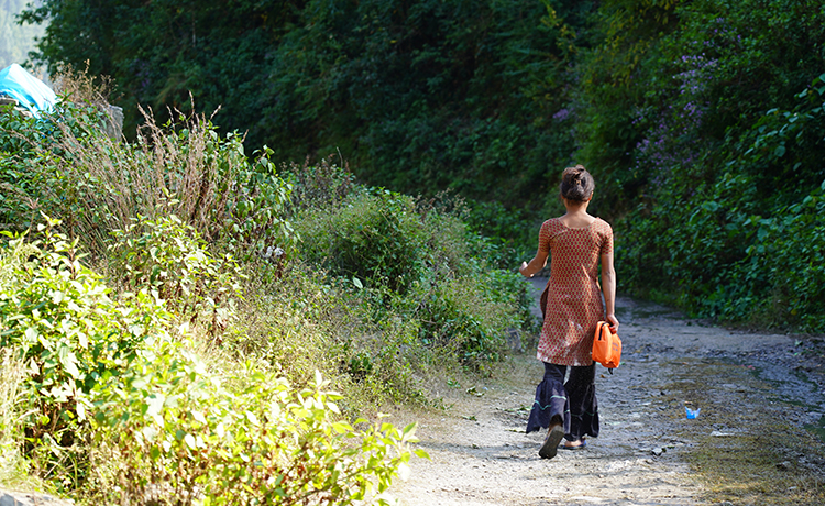 Young girl walks home on a grassy path