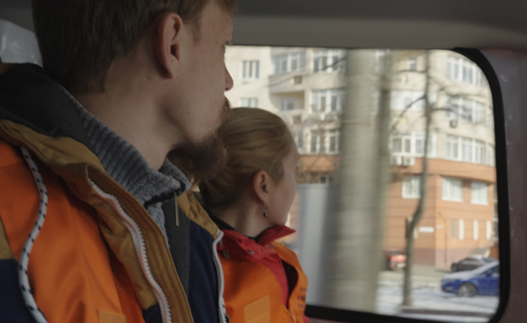 A man and a woman look out the window of a vehicle