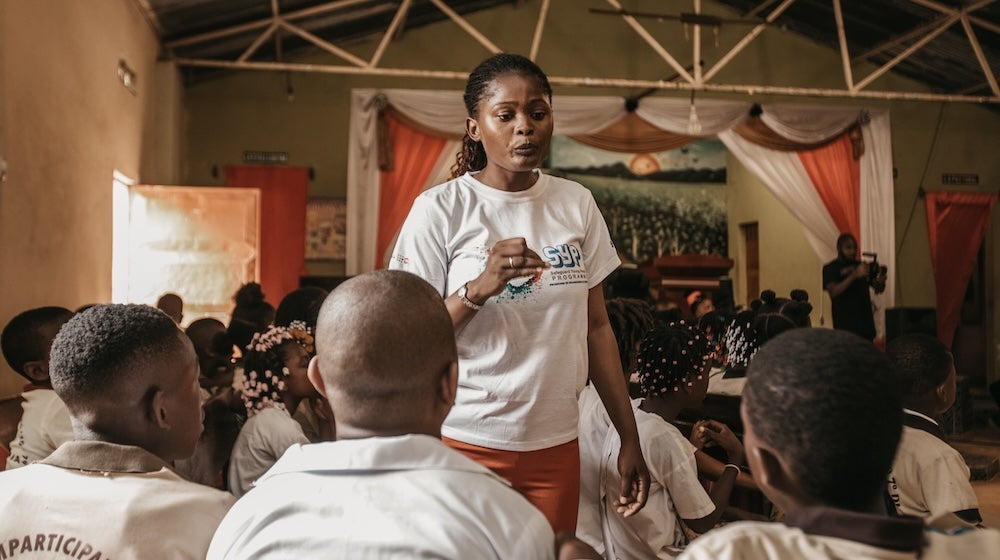 A woman from Angola leads a discussion, speaking to a group of young people. 