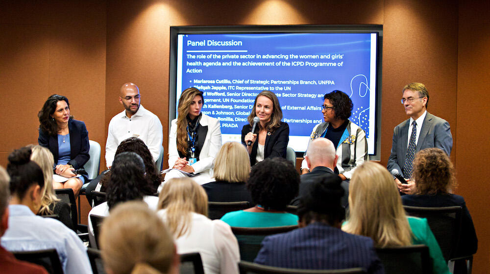 Participants of the UNFPA side-event are gathered in front of an audience.