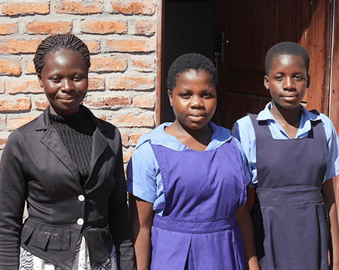 Two students stand with their teacher.