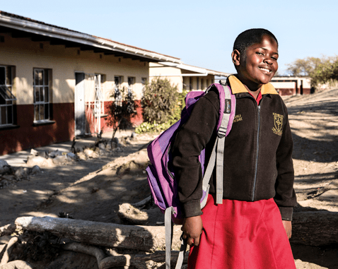 A girl stands outside her school.