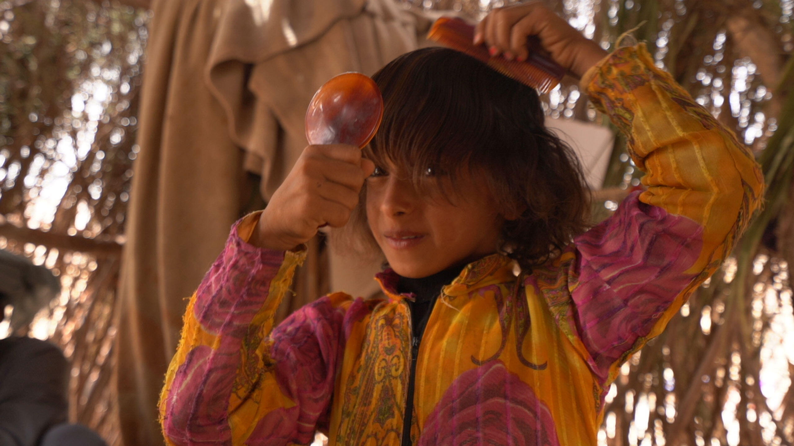 A young girl in a displacement camp in Marib Governorate, Yemen, enjoys a moment of self-care with a dignity kit provided as part of an emergency relief package by UNFPA. The kits include a flashlight, soap, a toothbrush and other personal and menstrual hygiene products to help women and girls maintain their well-being while displaced. 