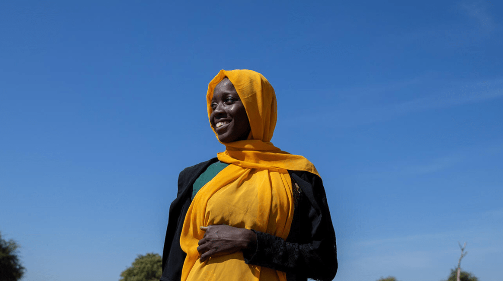 Woman wearing a yellow hijab smiling.