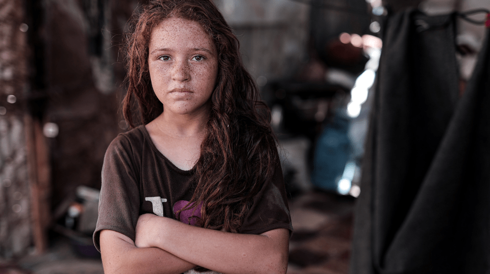 Une jeune fille regarde l’objectif, les bras croisés