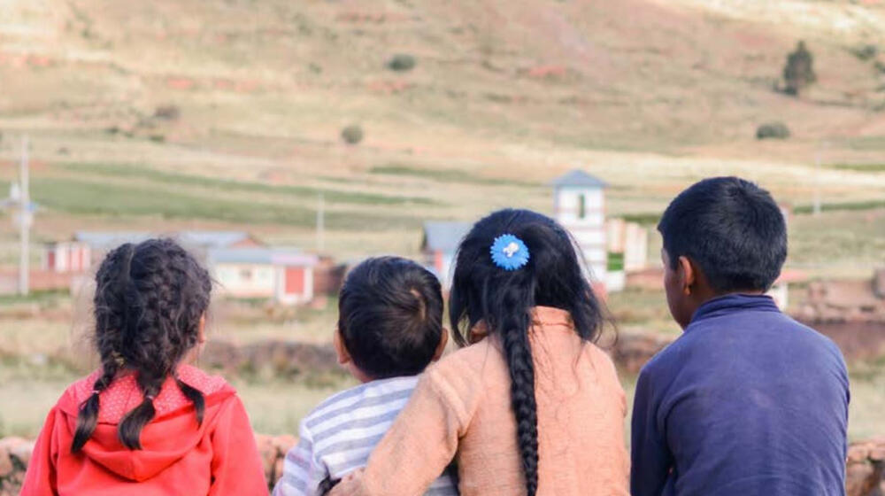 A group of male and female children sit together.