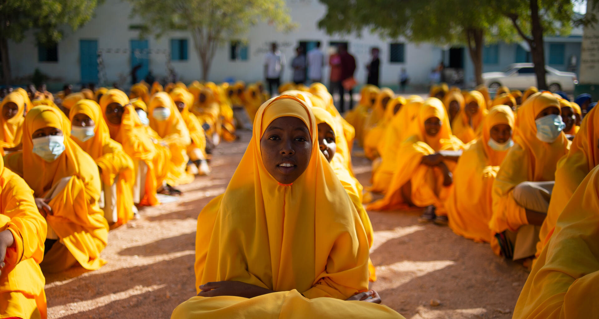 Young girls sit on the ground.