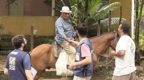 Un hombre a caballo saluda a otro hombre mientras otros dos hombres observan